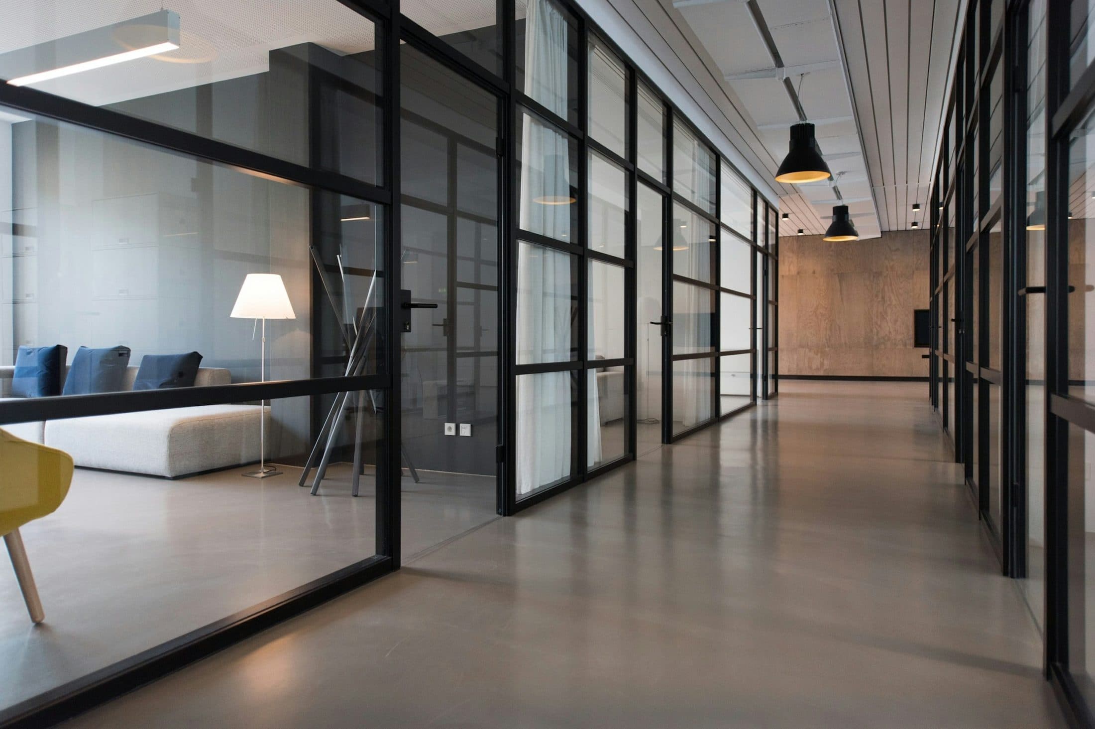 Couloir de bureaux bordé de portes vitrées à châssis noirs