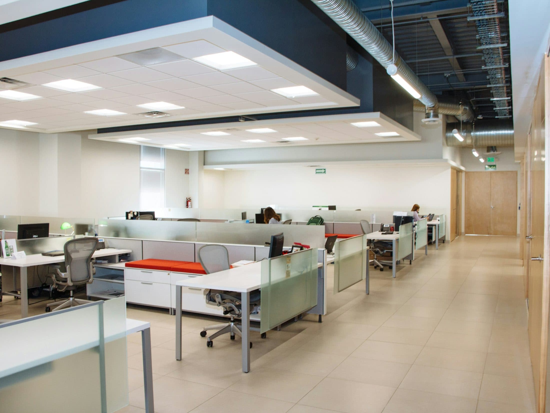 Open space aux postes alignés derrière des cloisons de verre dépoli