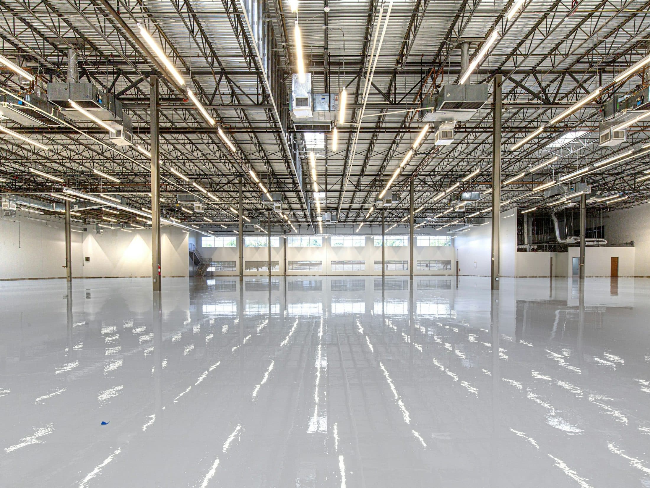 Polished warehouse floor reflecting the overhead light runs